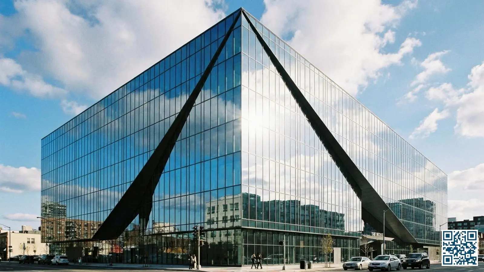 Modern kantoorgebouw met grote glazen gevels die de bewolkte lucht weerspiegelen in daglicht