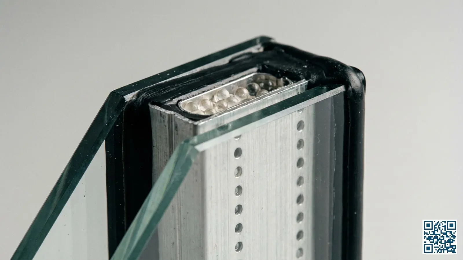 Close-up van een isolerende glasunit met zichtbare aluminium spacer, randafdichting en spouw tussen de glasbladen