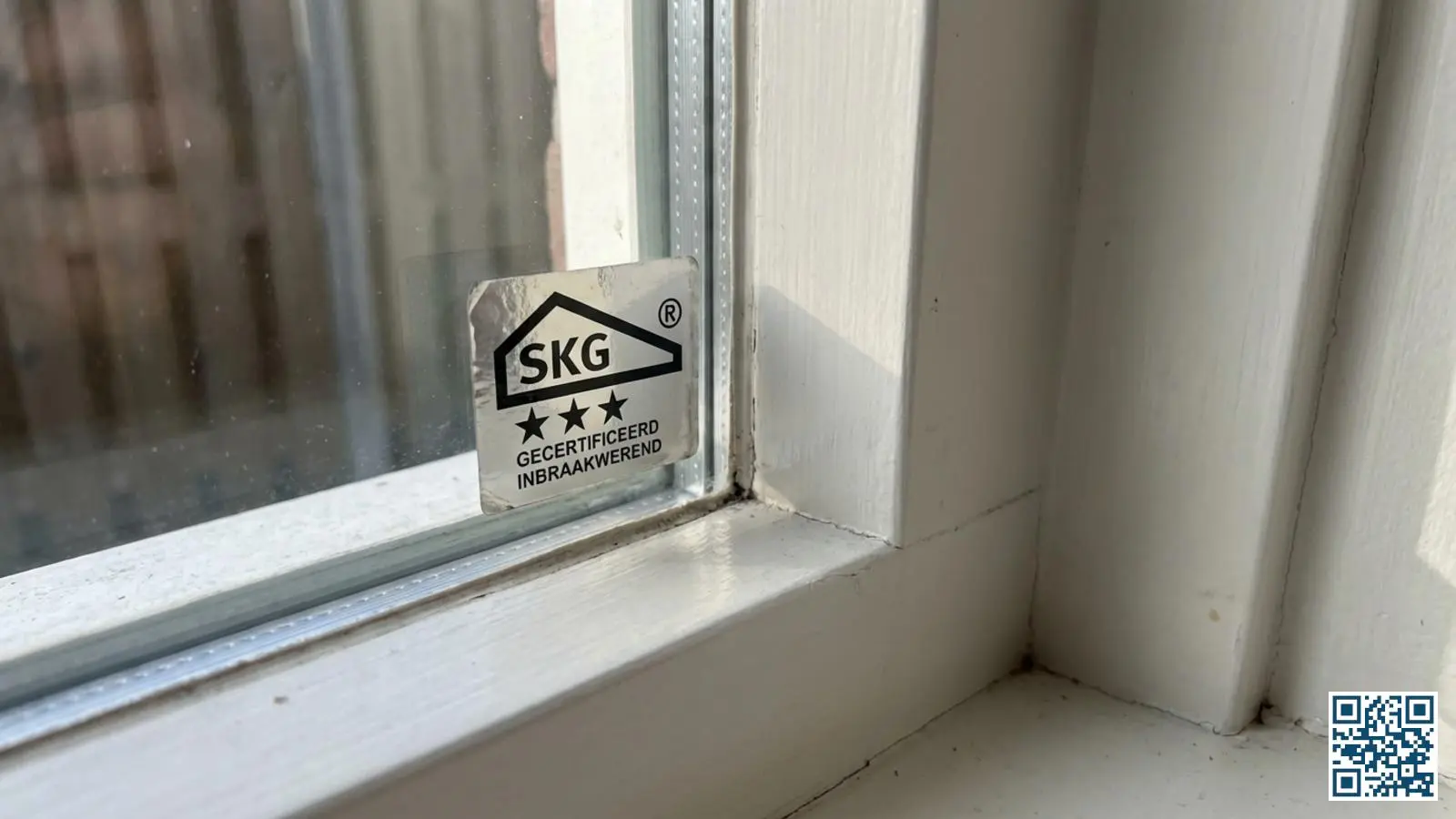 Close-up van een raamkozijn met een zichtbaar SKG-keurmerk dat de inbraakwerendheid aangeeft