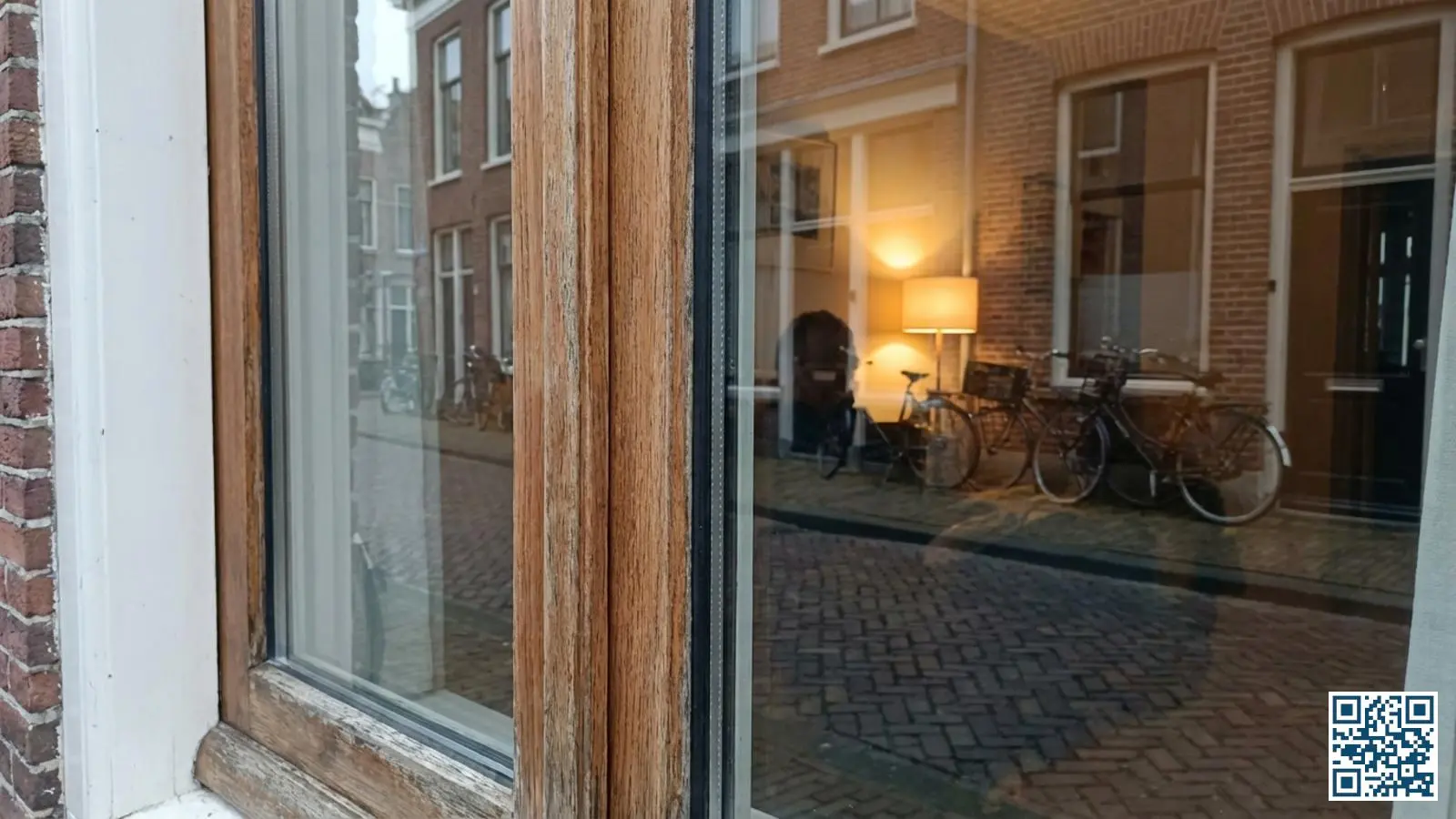Dubbel HR+ glas geplaatst in een klassiek houten kozijn van een Nederlandse woning met zicht op straat