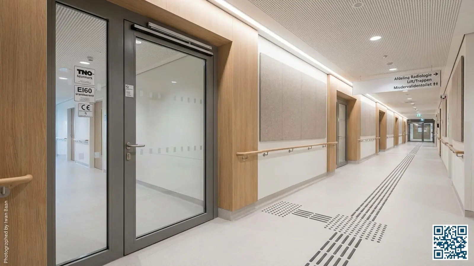 Brandwerende glazen deur in gang van zorginstelling met zichtbare certificering op het kozijn